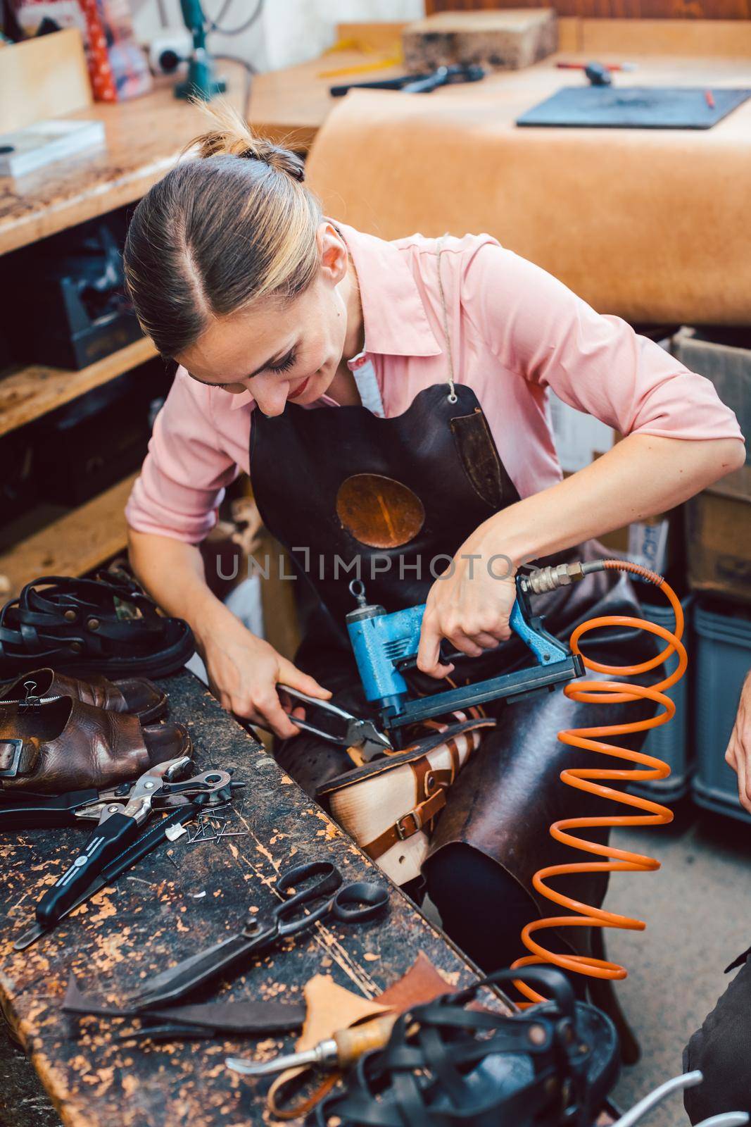 Cobbler woman repairing a shoe fixing the sole