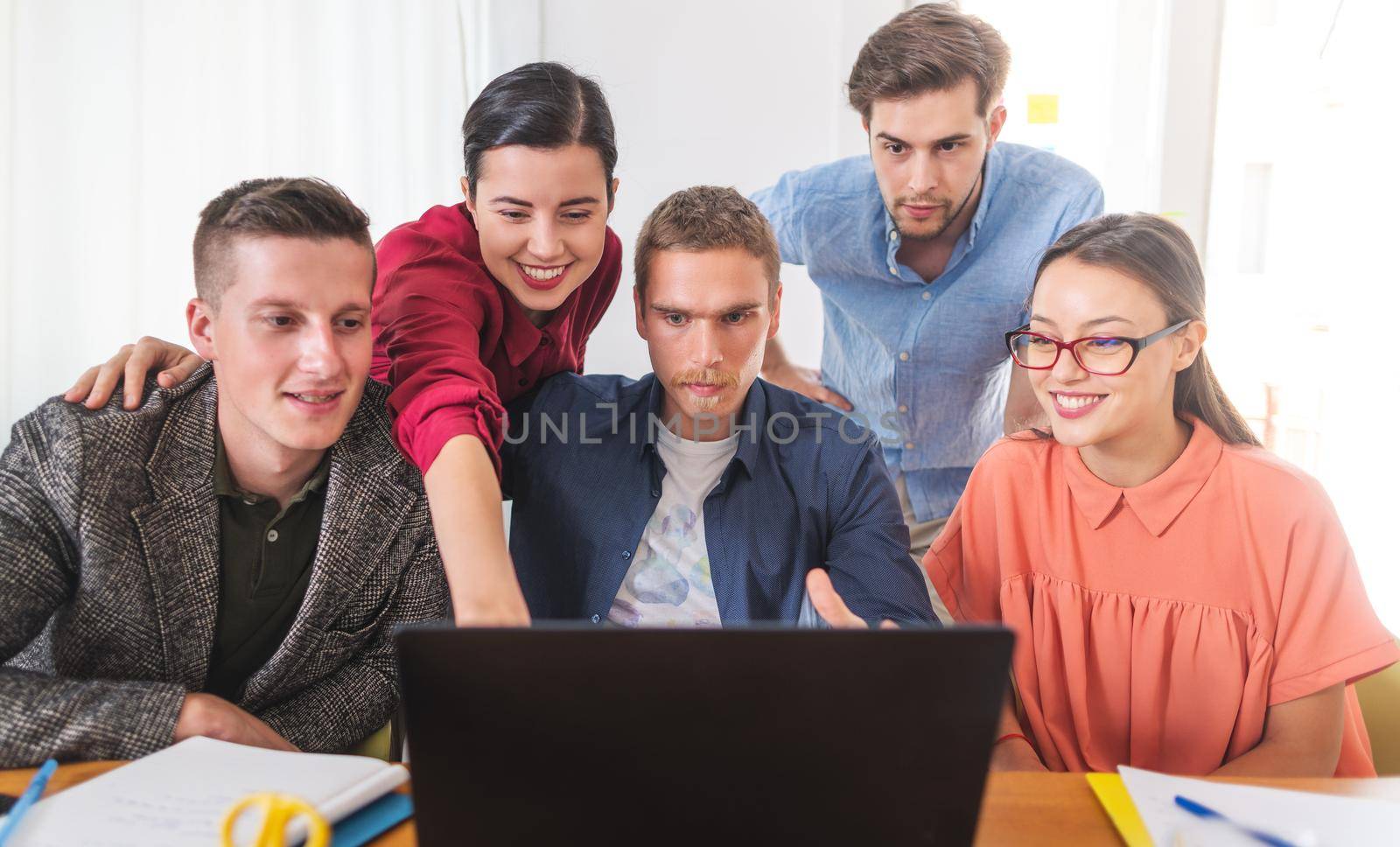 Young business woman showing to her other colleagues on laptop