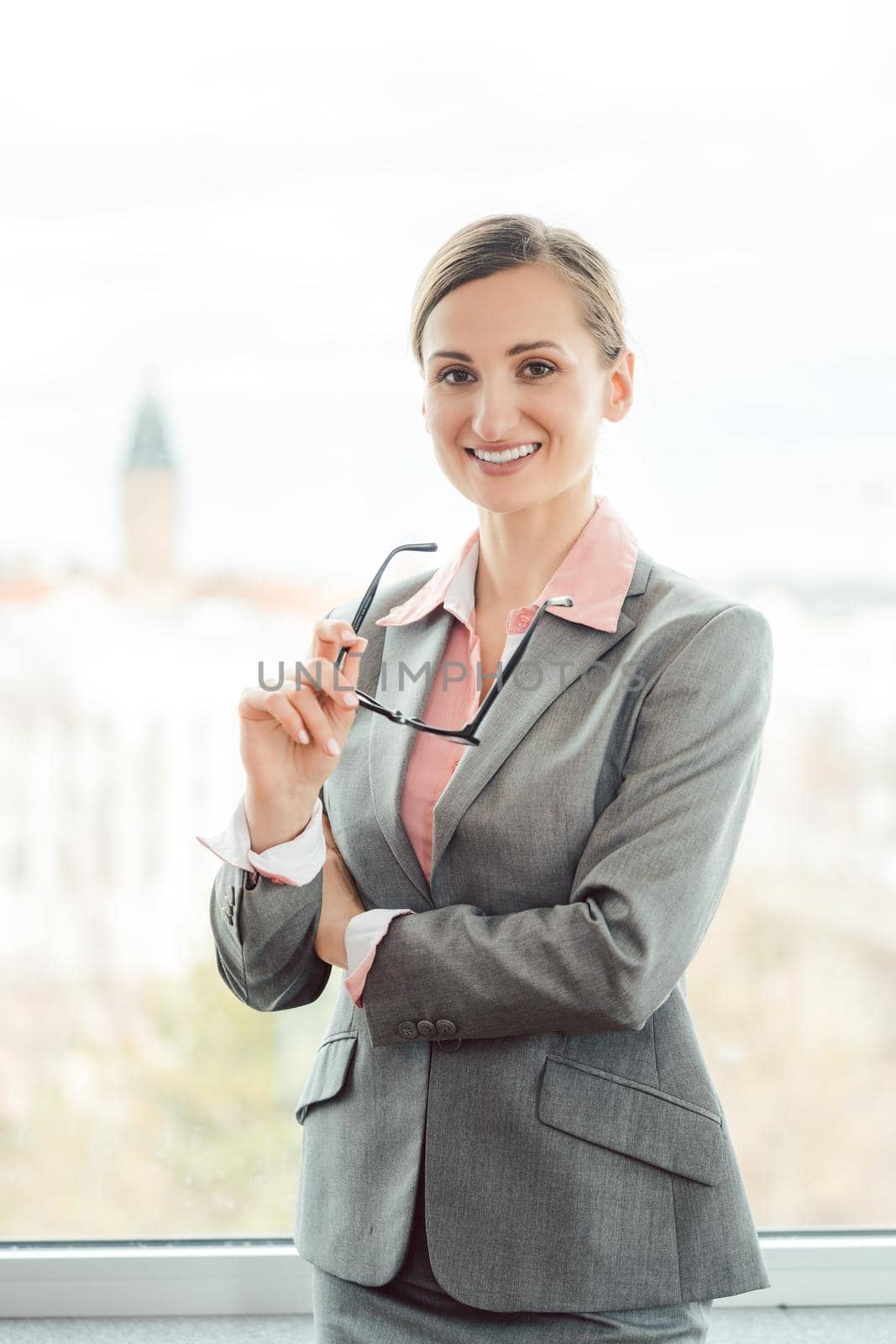 Business woman wearing sharp suit in her office by Kzenon