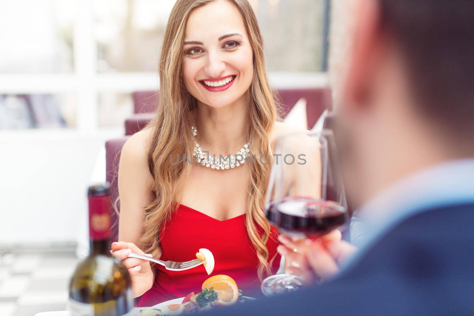 Couple toasting with red wine in romantic restaurant by Kzenon