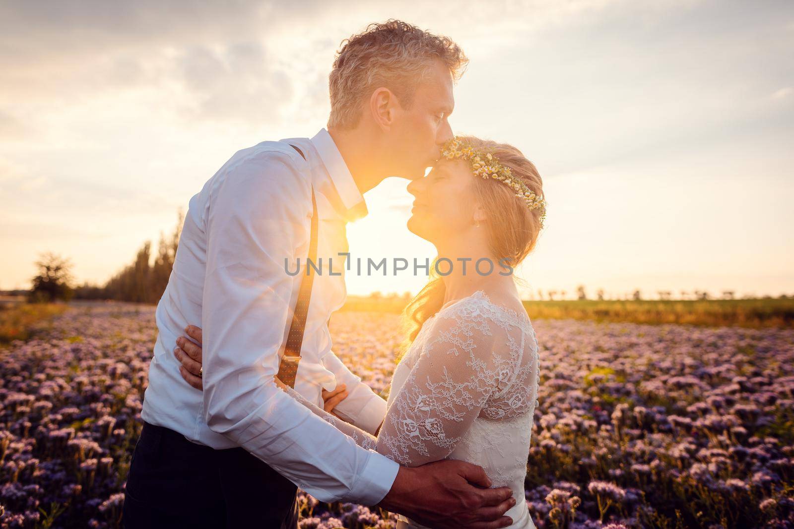 Bridegroom kissing his bride during romantic wedding in the village in a romantic setting