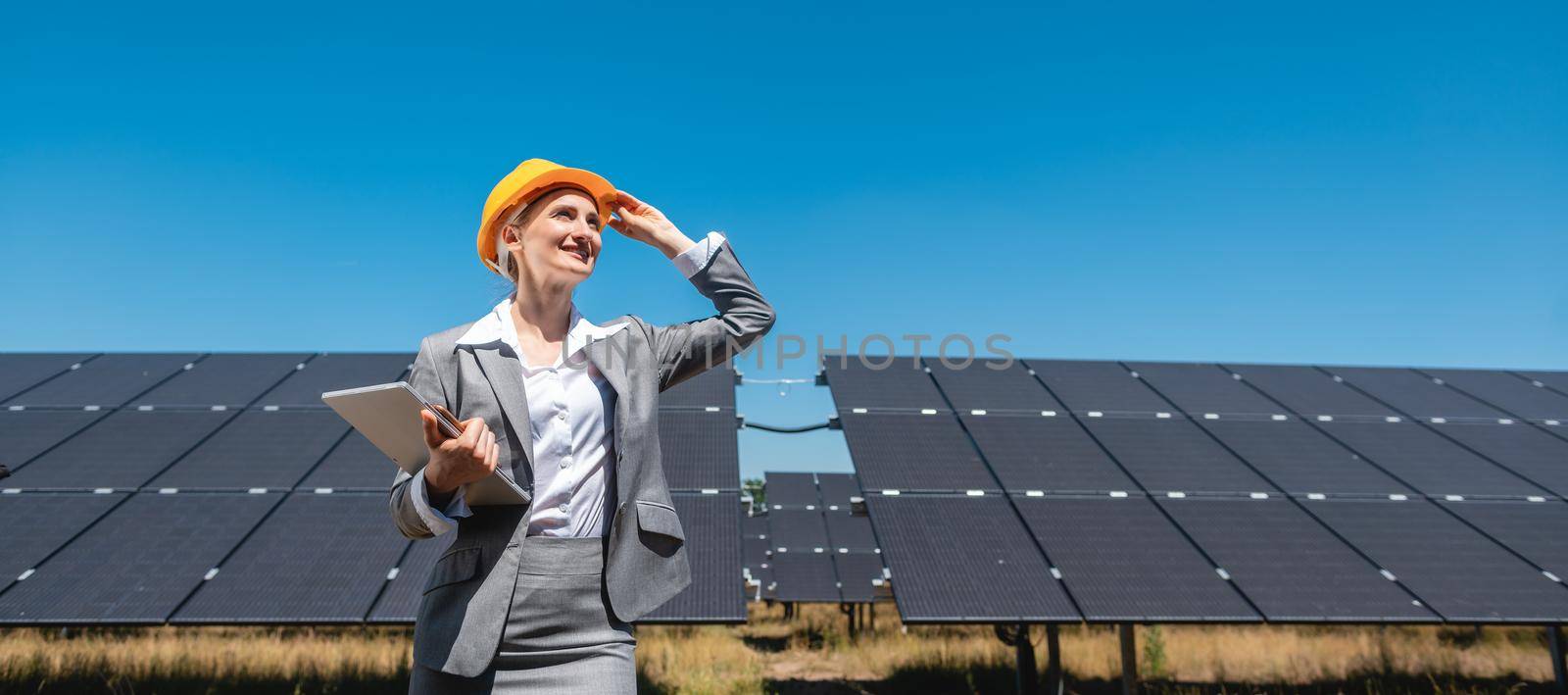 Businesswoman or investor inspecting her solar farm standing in front of photovoltaic panels