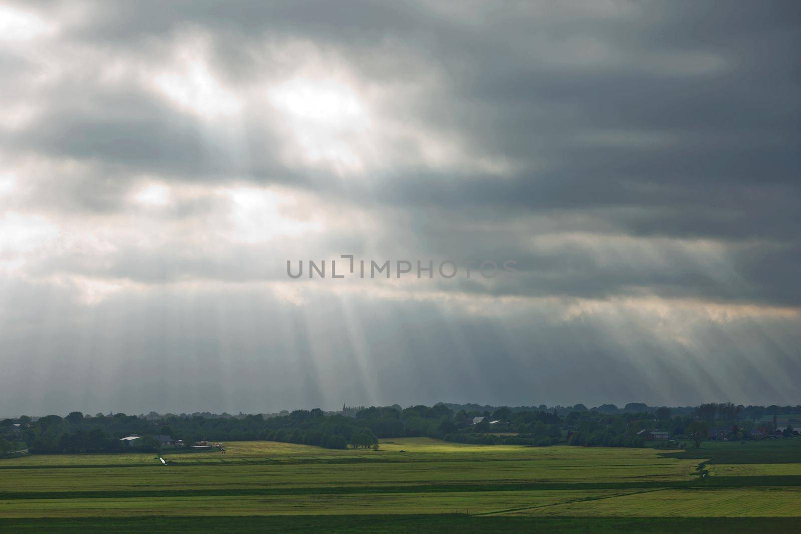 Beautiful countryside and sunrays passing through clouds on landscape with fields near Kiel - Schleswig-Holstein - Germany.