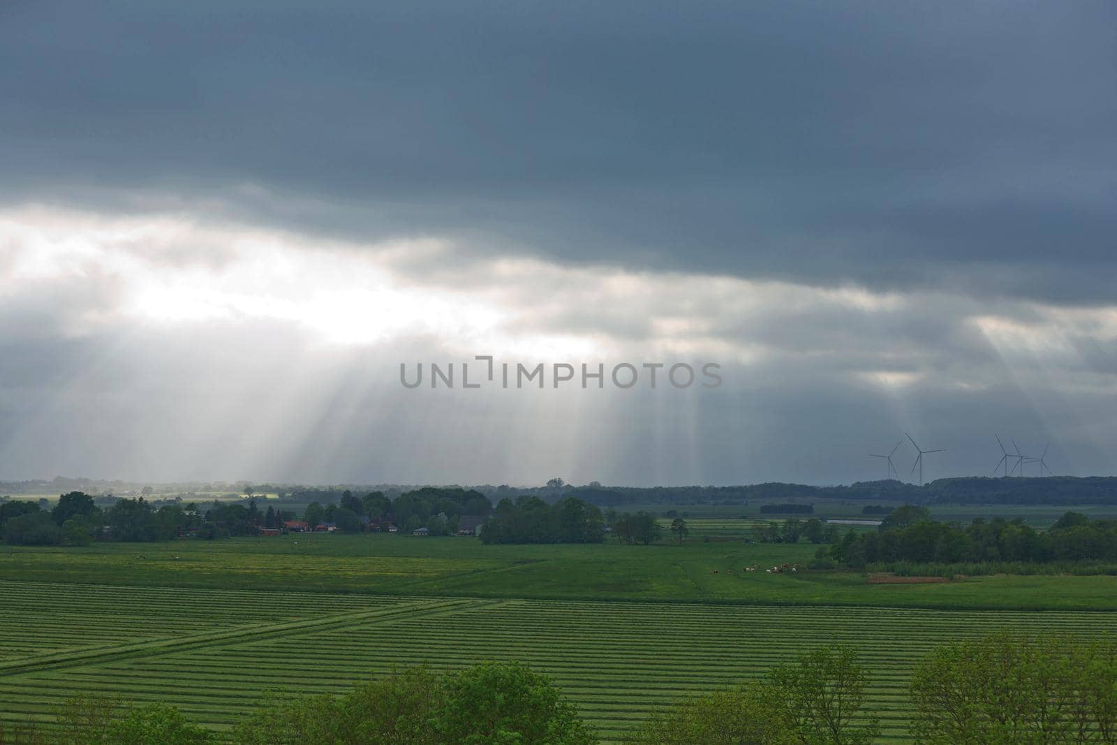 Beautiful countryside and sunrays passing through clouds on landscape with fields near Kiel - Schleswig-Holstein - Germany.