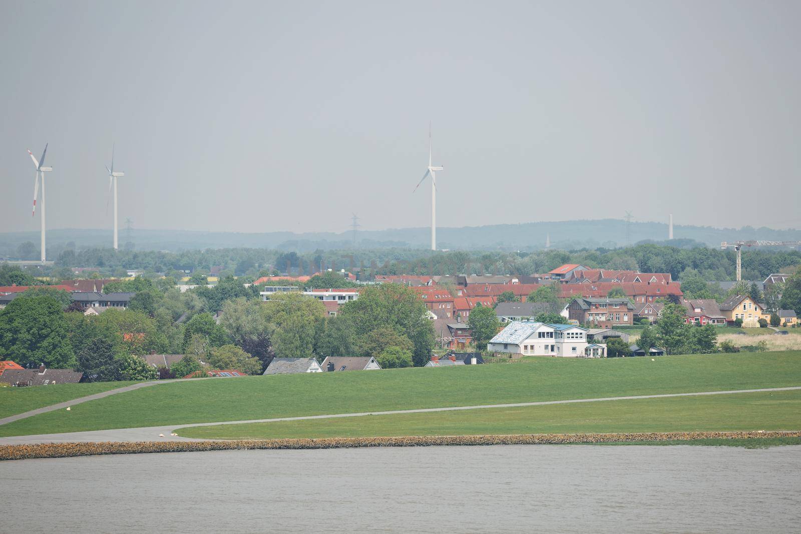 Windmills power plant and turbines generating renewable green energy near to Kiel canal in Germany.