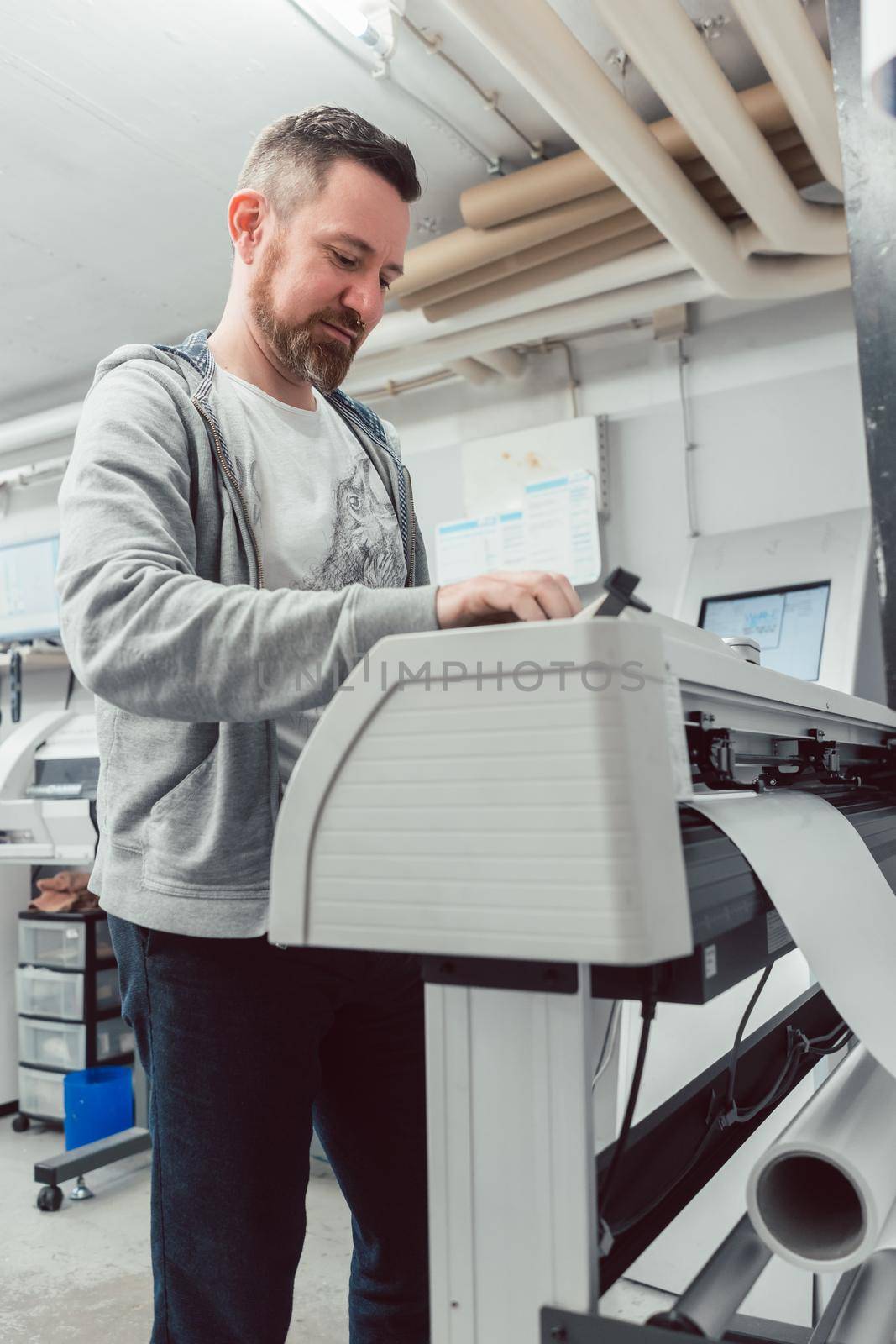 Man preparing large format printer for a print job by Kzenon
