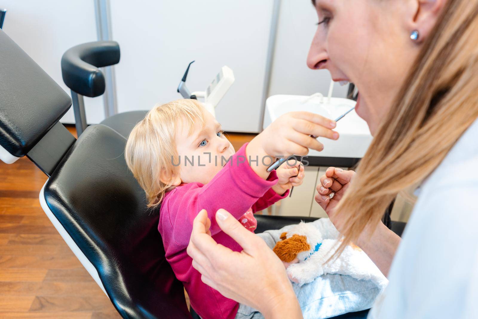 Child in the dentists office becoming comfortable playing with the tools