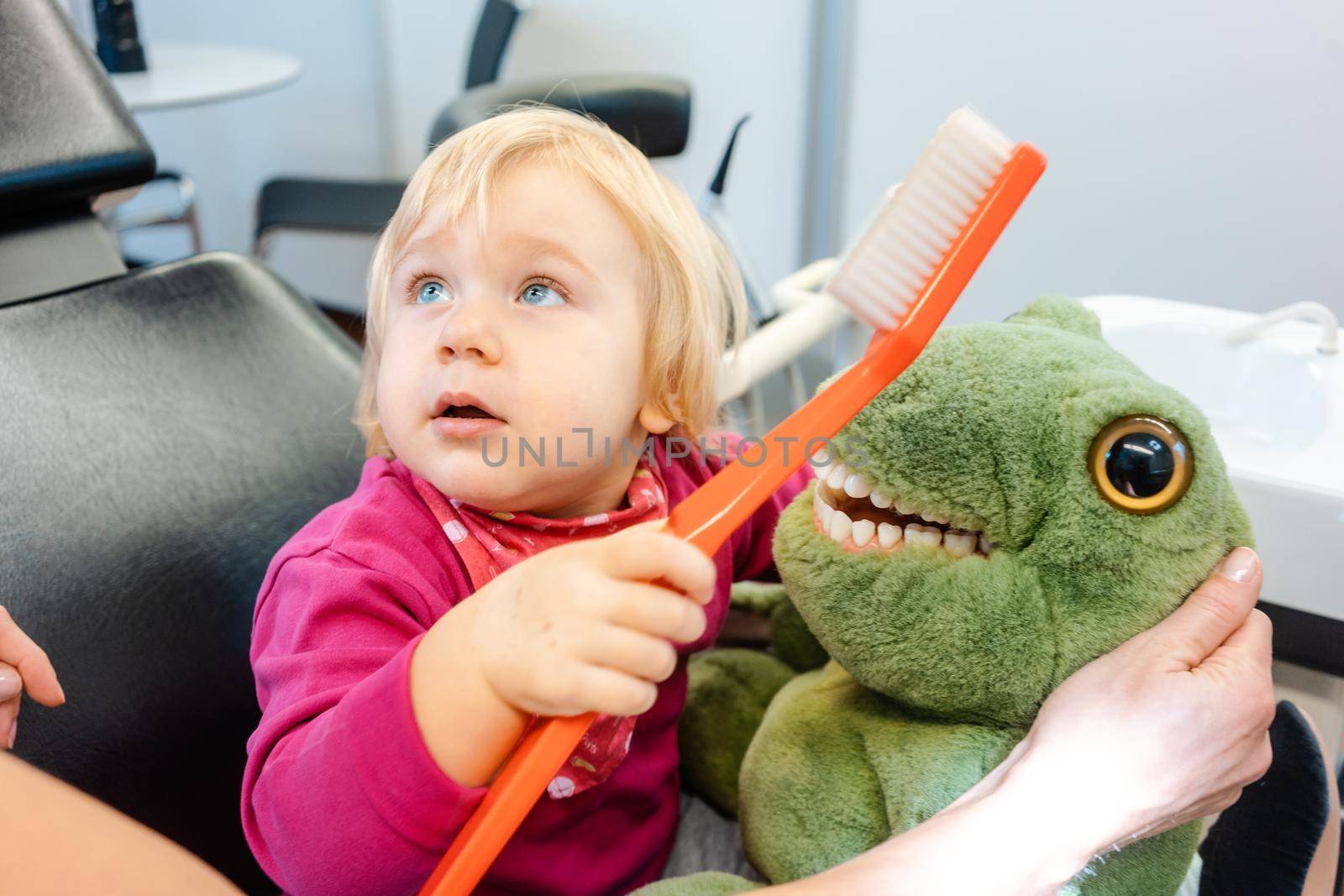 Child at the dentist brushing teeth of a plush toy by Kzenon