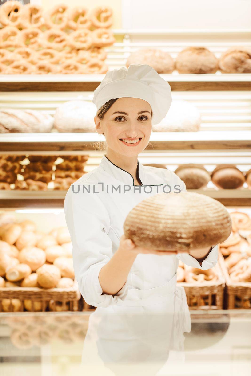 Beautiful woman selling bread in bakery offering a loaf