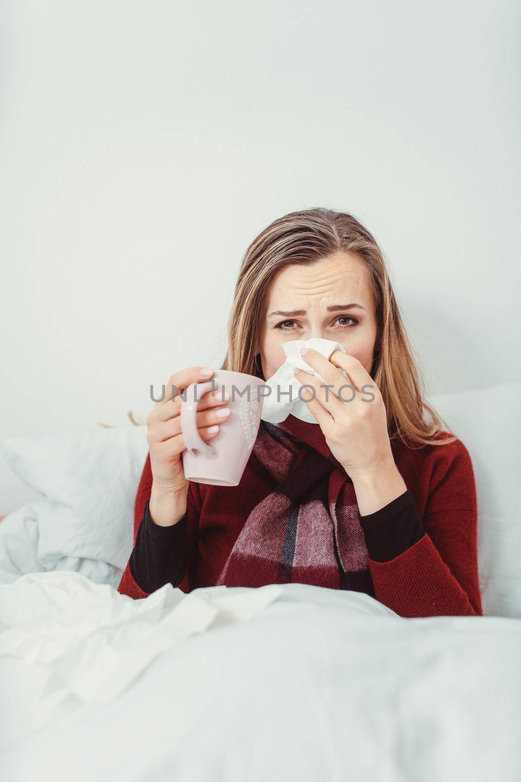 Woman with hot tea and the flu lying in bed sick with fever