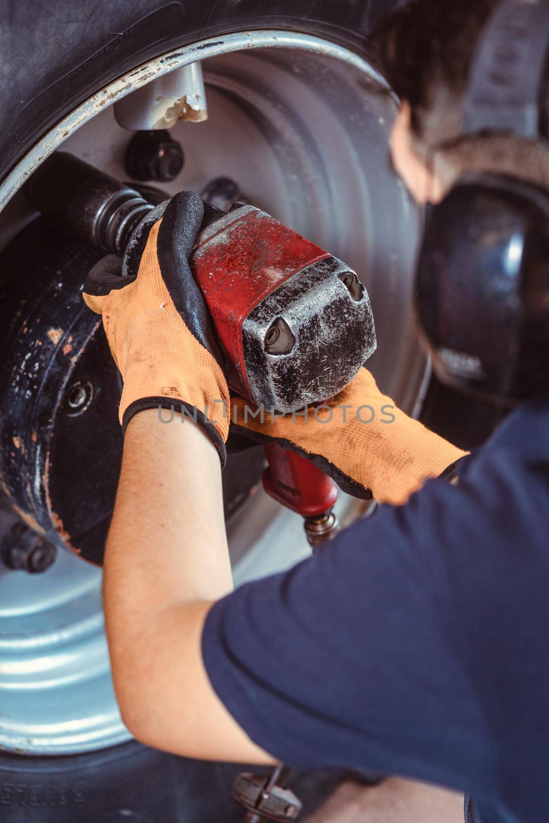 Close-up of farm machine mechanic working on wheel with power tool