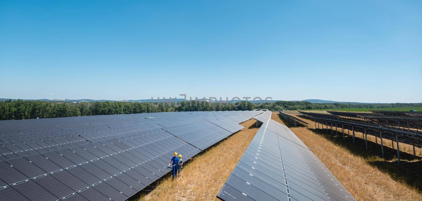 Large photovoltaic power plant with people standing at the panels by Kzenon