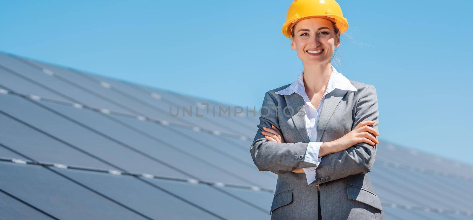 Woman investor in clean energy standing proudly in front of solar panels