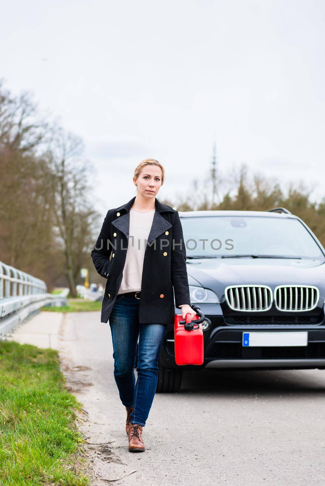 Woman out of fuel with car starting walking towards next gas station to get fuel