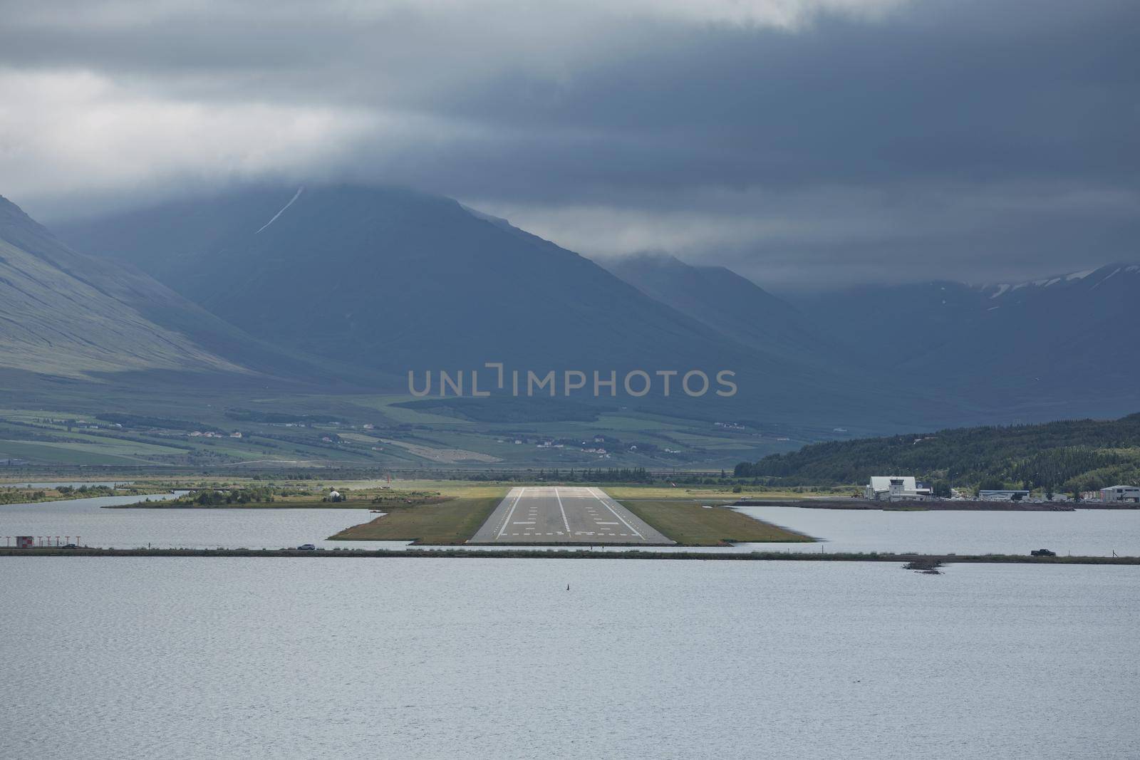 View from the end of runway at Akureyri airport in Iceland. A small plane is taking off.