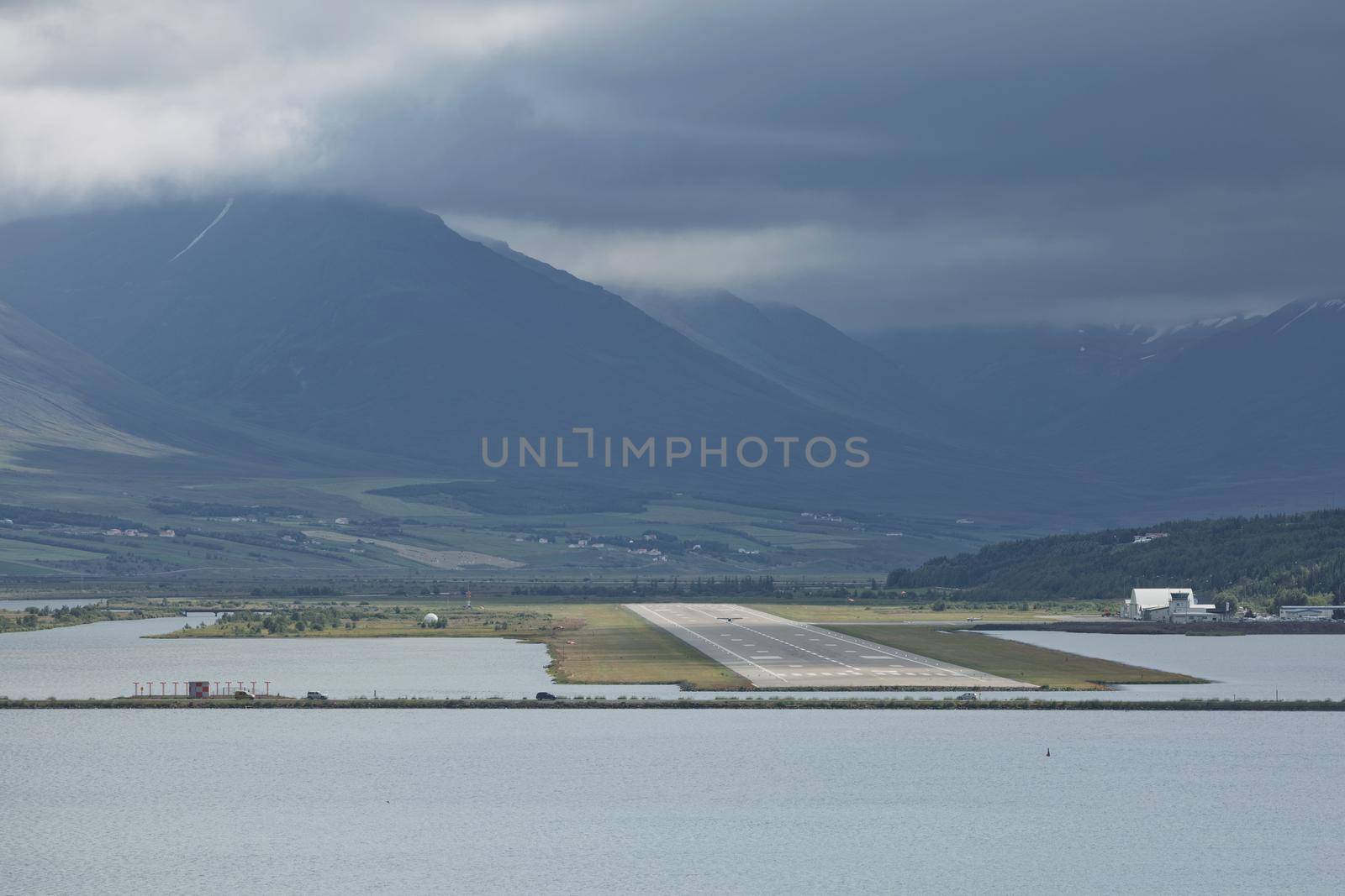 View from the end of runway at Akureyri airport in Iceland. A small plane is taking off.