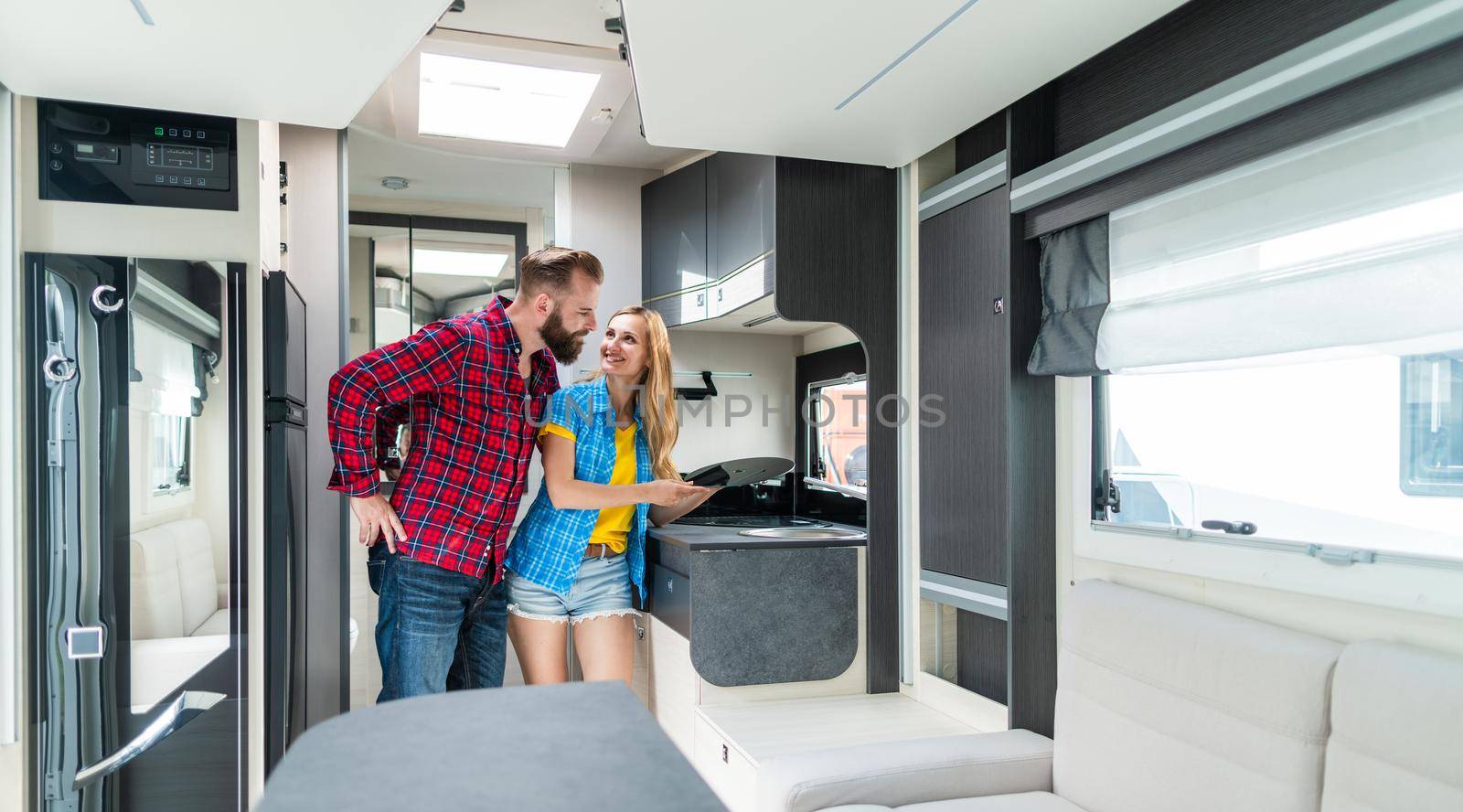 Woman and man testing interior of camper they want to buy or rent by Kzenon