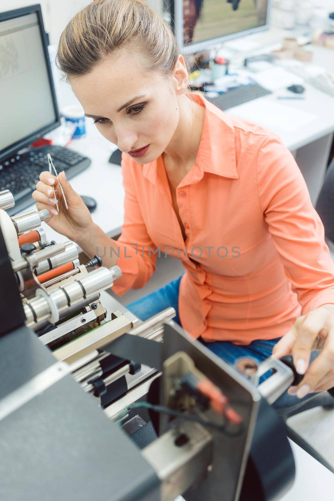 Worker woman putting new labels in printing machine by Kzenon