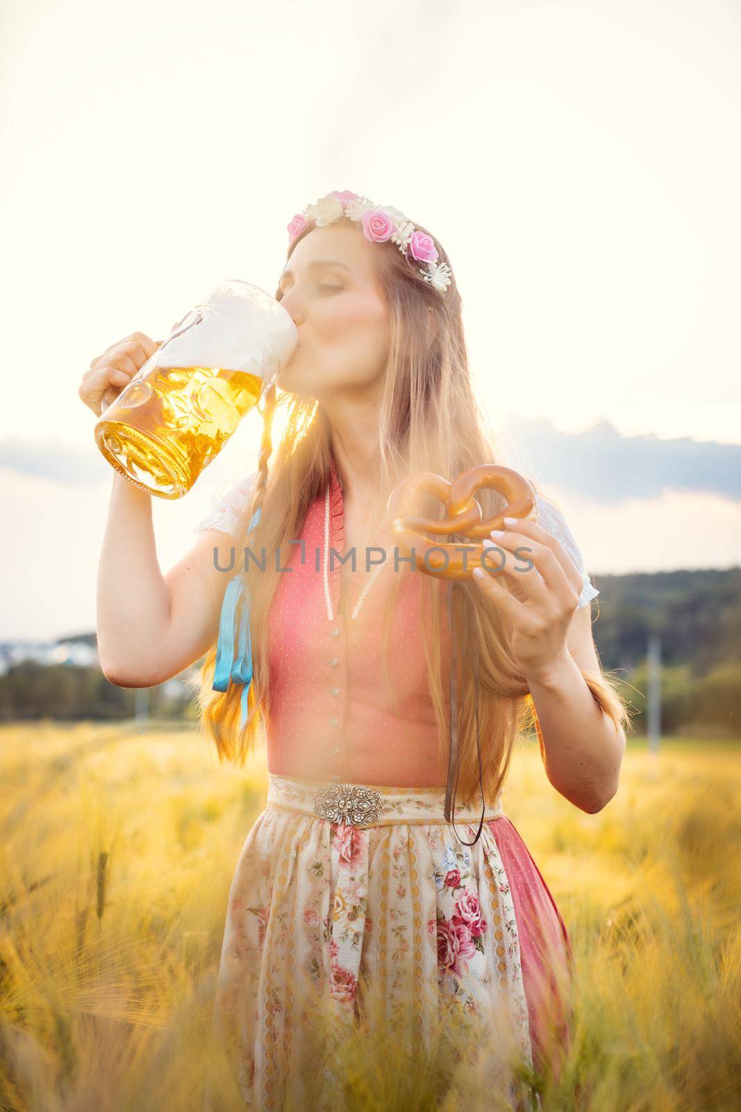Woman in traditional clothing drinking beer in Bavaria by Kzenon