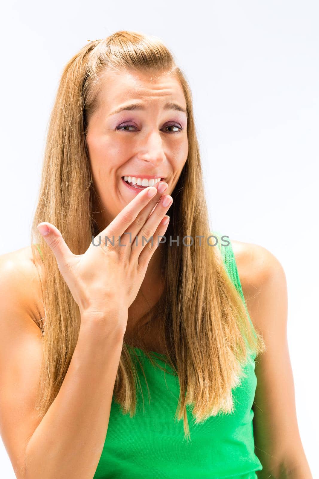 Close-up of blonde young woman laughing with hand over the mouth isolated over white background