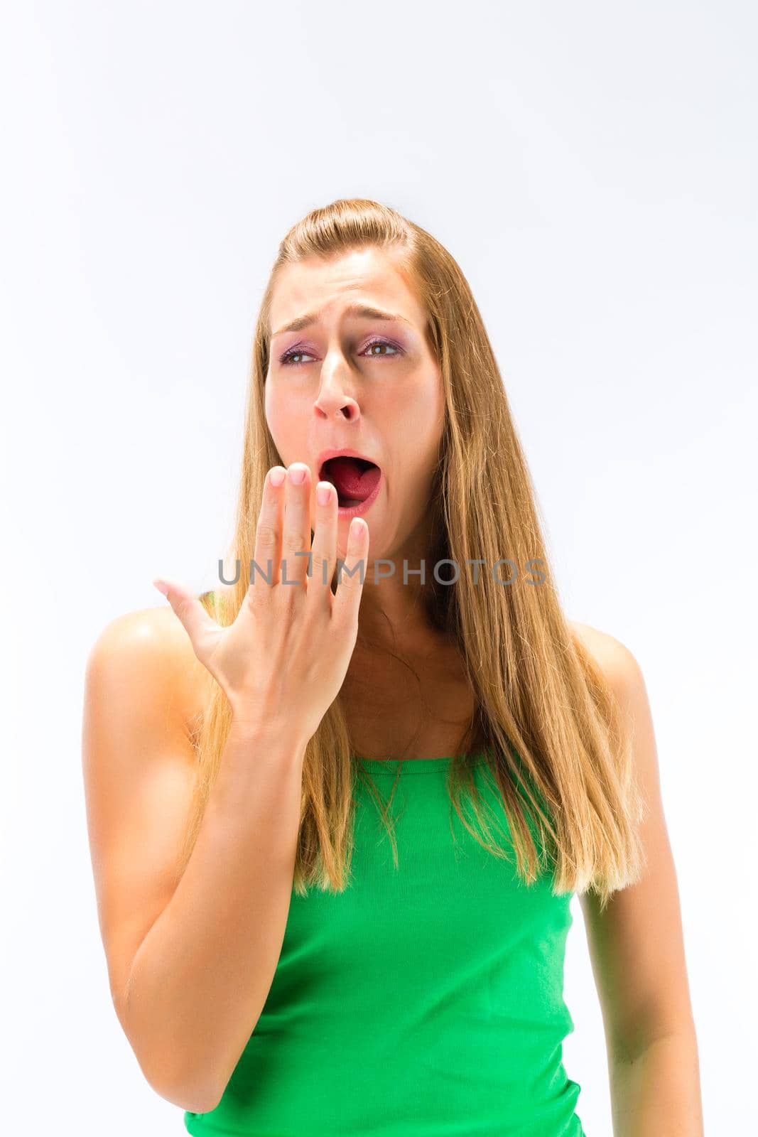 Portrait of sleepy young woman yawning against white background