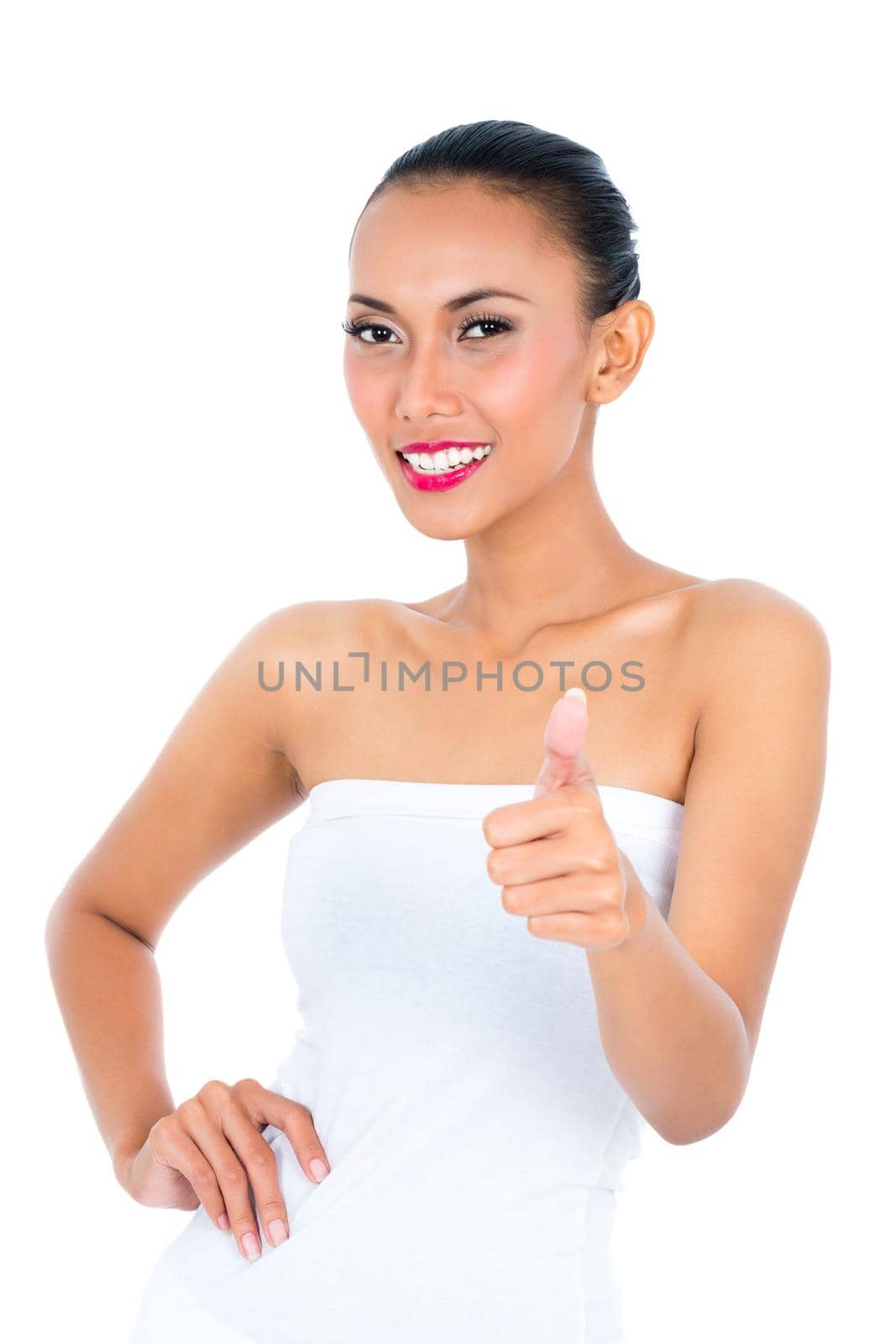 Smiling young woman gesturing thumbs up over white background