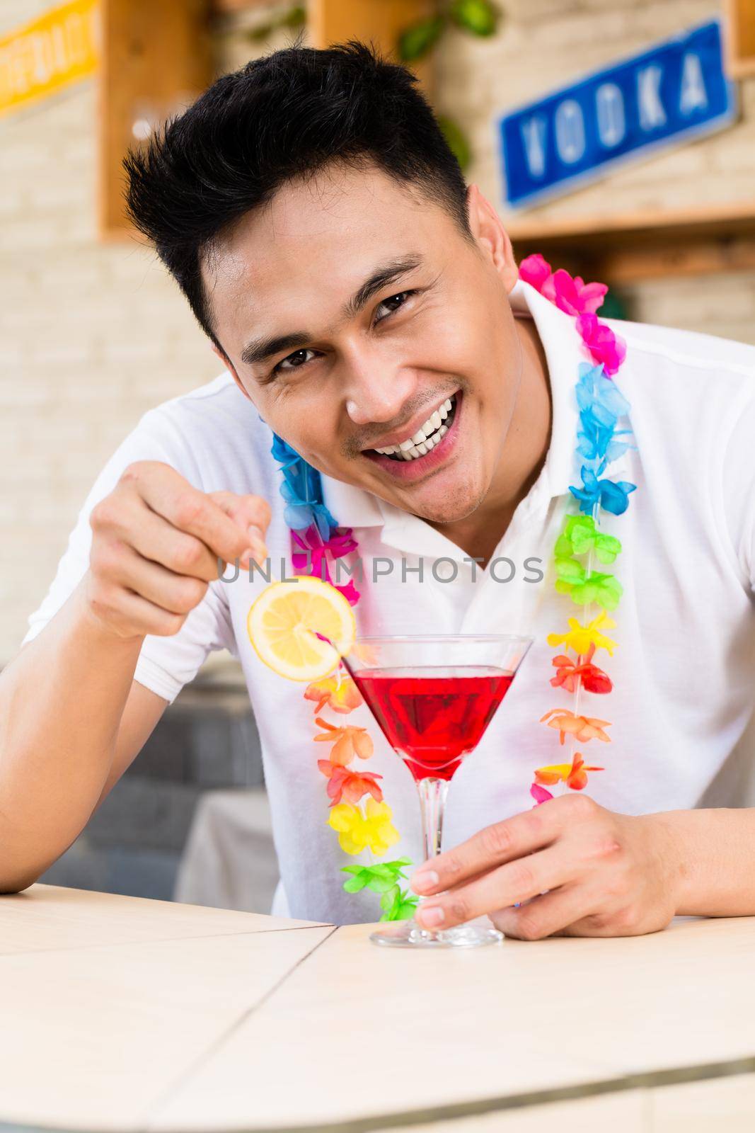 Close-up of a happy man stirring cocktail