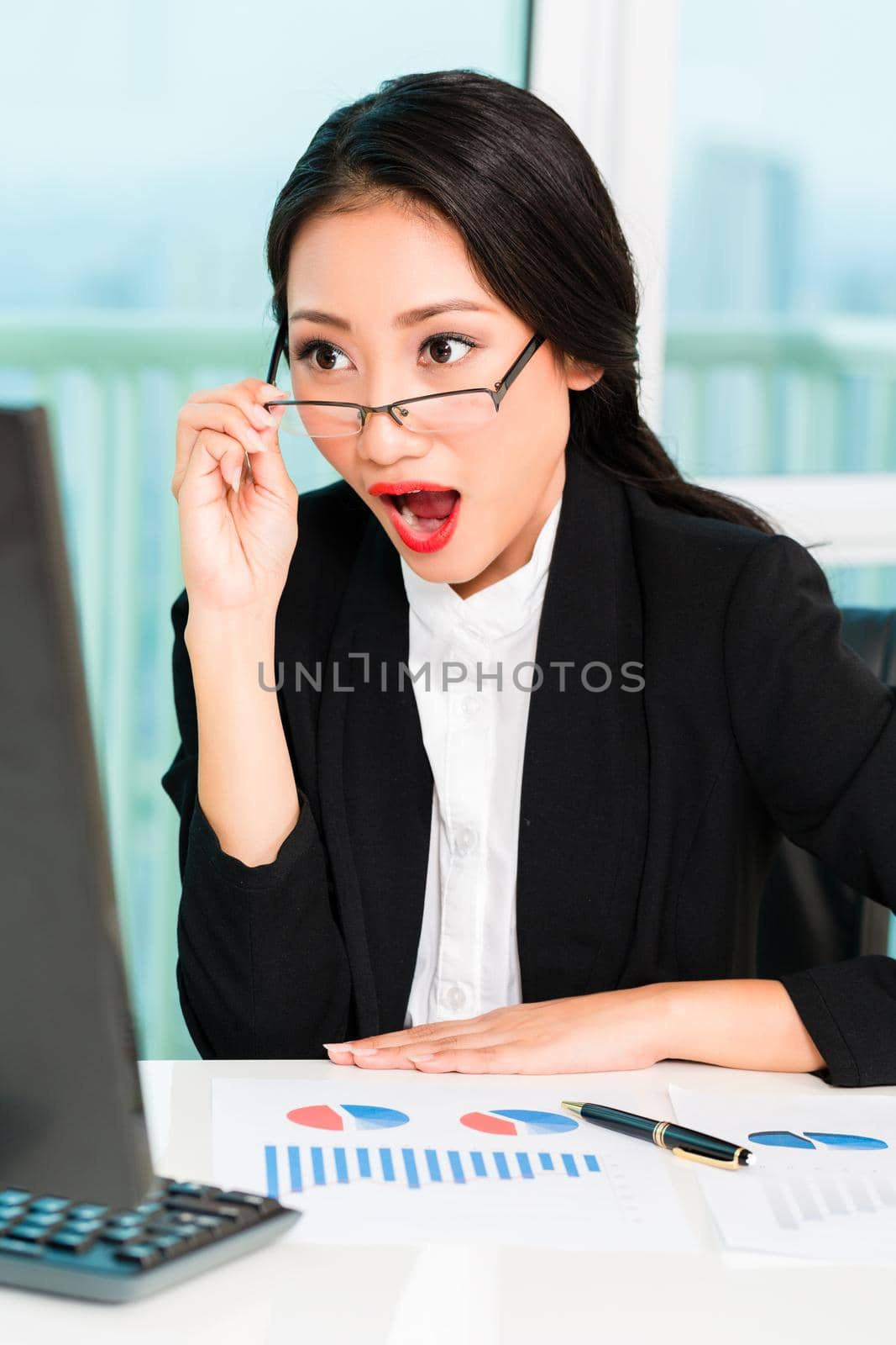 Surprised businesswoman looking at desktop by Kzenon