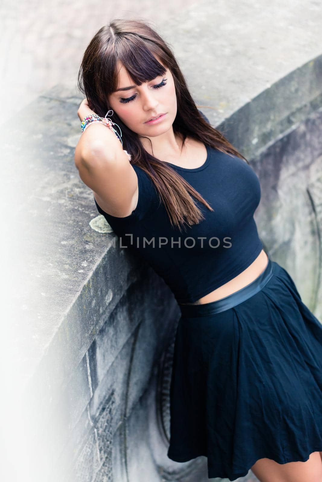 Close-up of an attractive young woman with eye closed standing near wall outdoors
