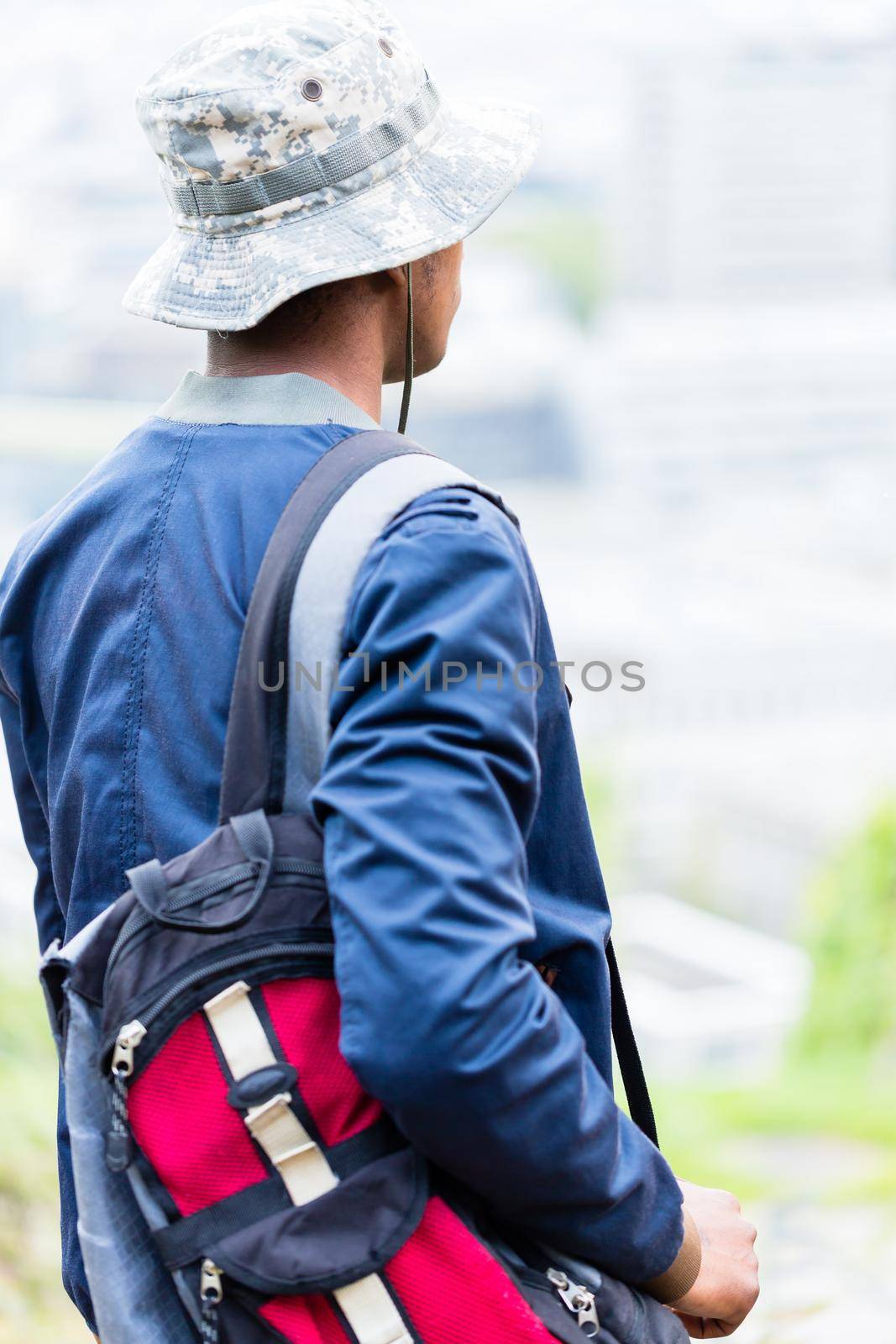Rear view of boy with his backpack wearing camouflage hat