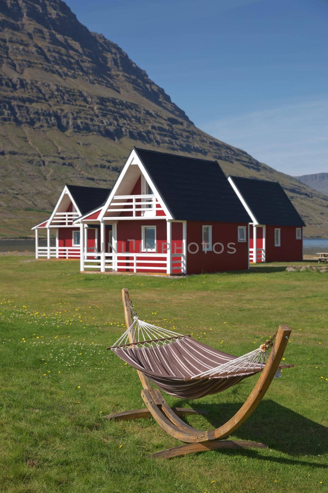 Traditional red painted wooden panel house with mighty Holmatindur mountain in the background in Eskifjordur, East Iceland.