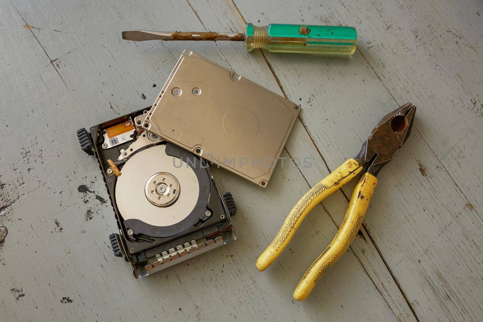 Broken and Destroyed Hard Drive Disk and Tools on Wooden Table.