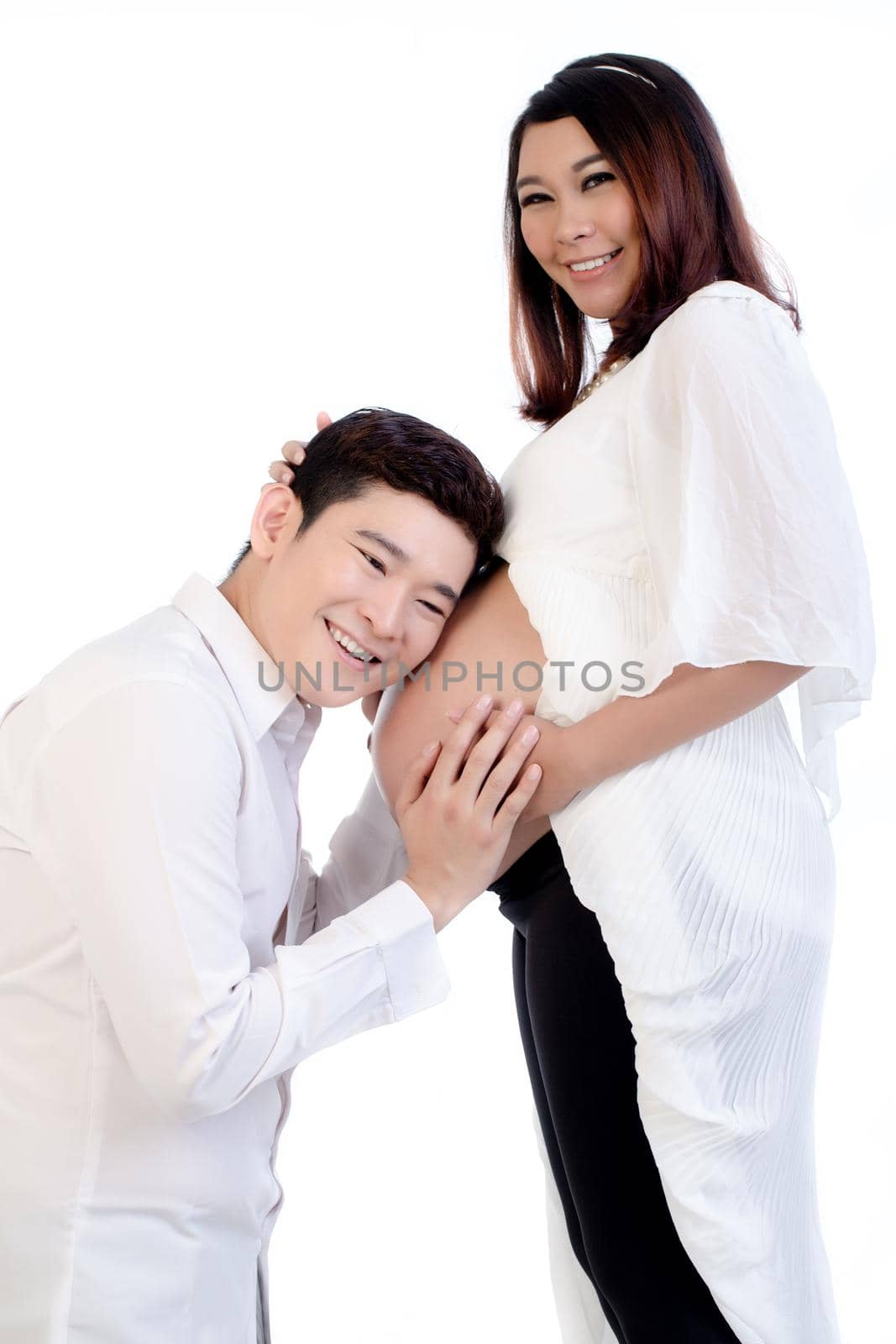 Smiling man listening to his wife's belly isolated over white background