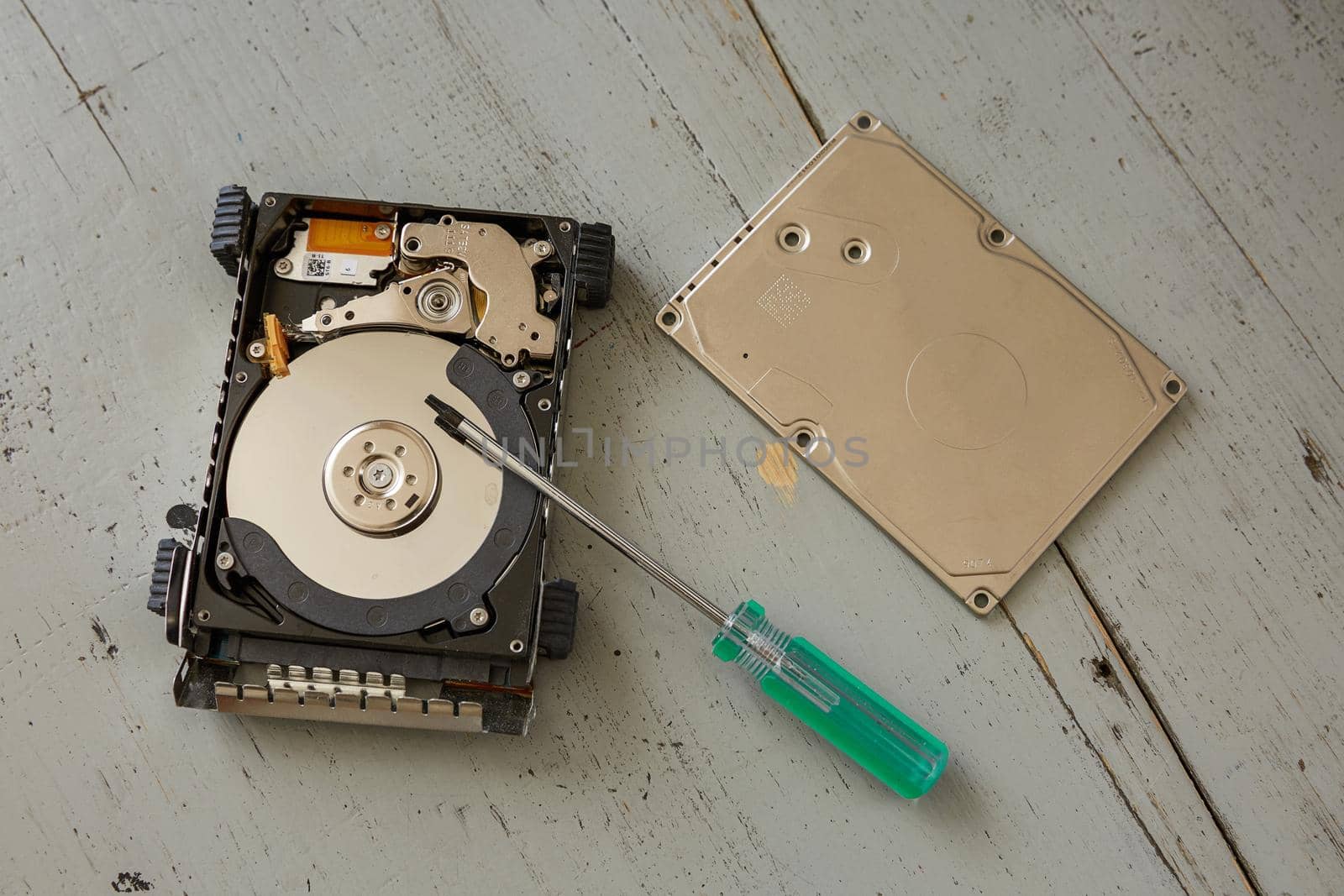 Broken and Destroyed Hard Drive Disk and Tools on Wooden Table.