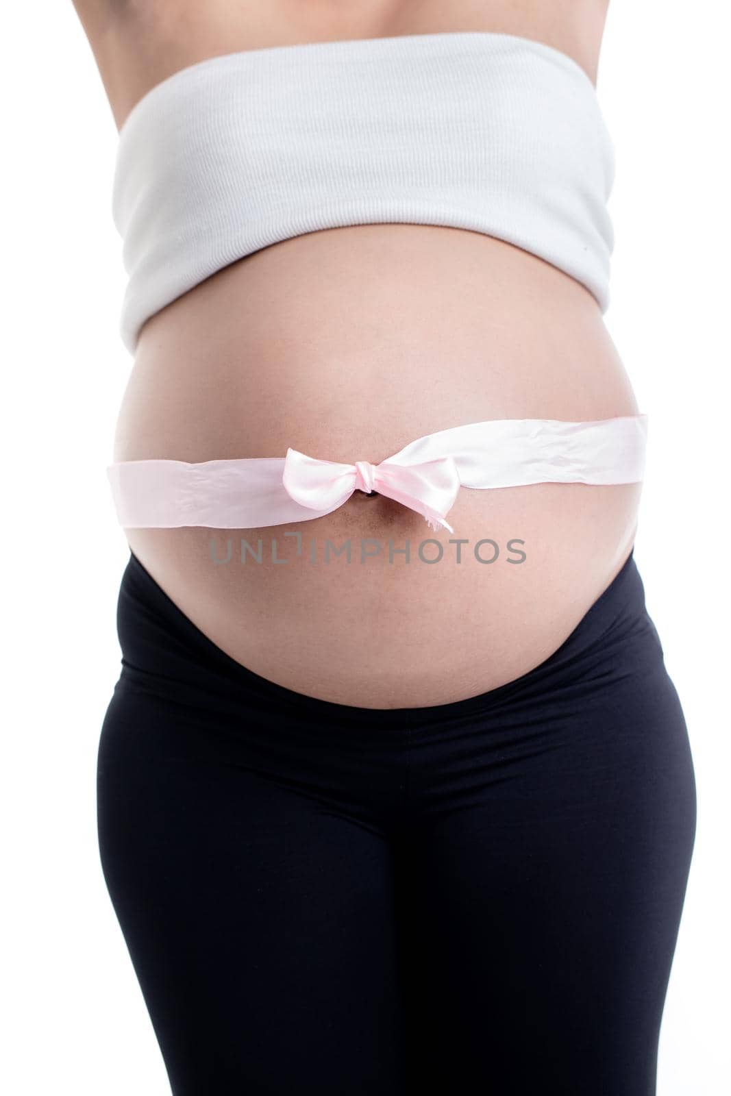 Close-up of pink ribbon bow over the pregnant woman's belly against white background