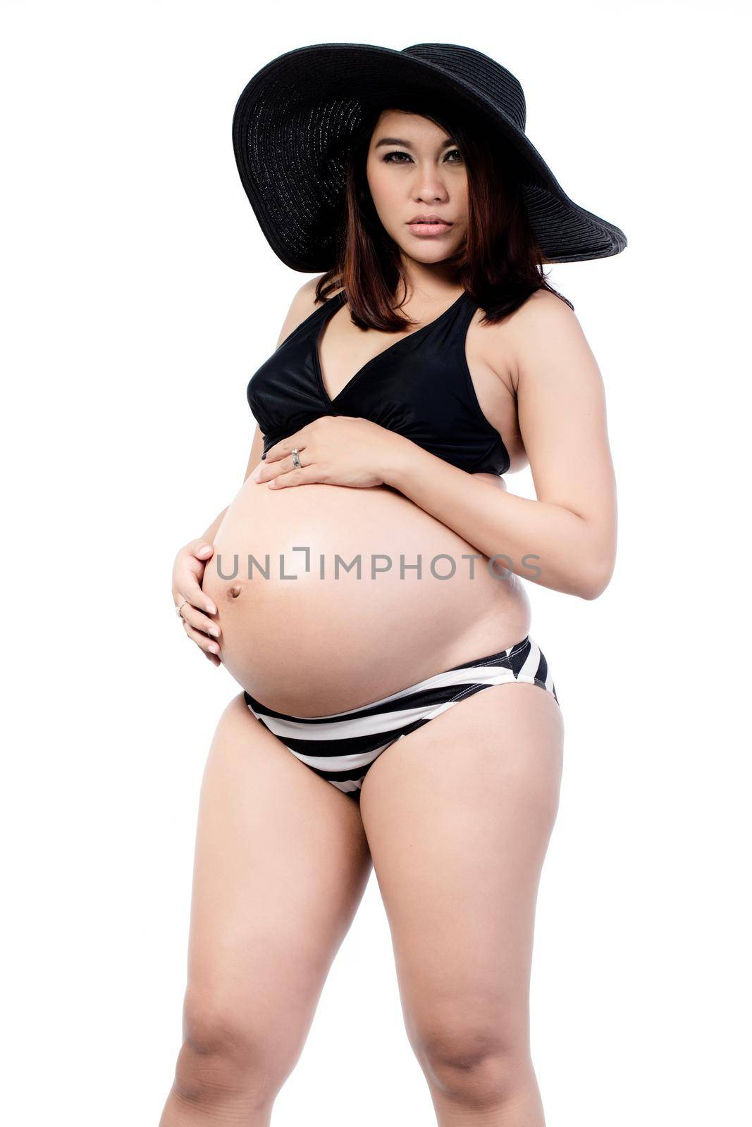 Portrait of pregnant woman in black bikini wearing hat isolated over white background