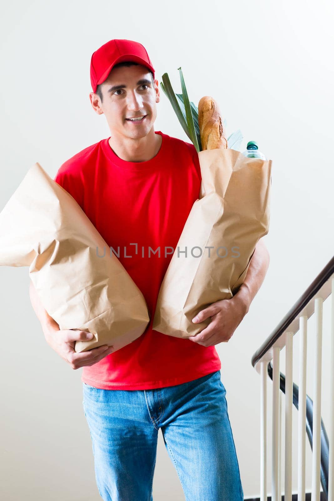 Front view of delivery man carrying two grocery shopping bags with food