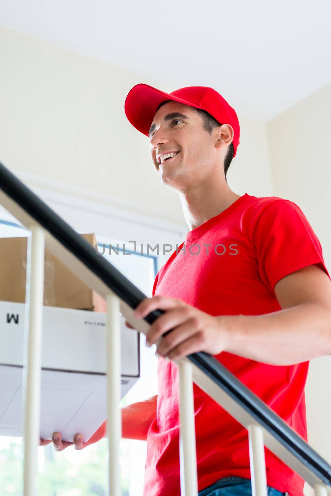 Smiling man in red uniform delivering mail post boxes at home