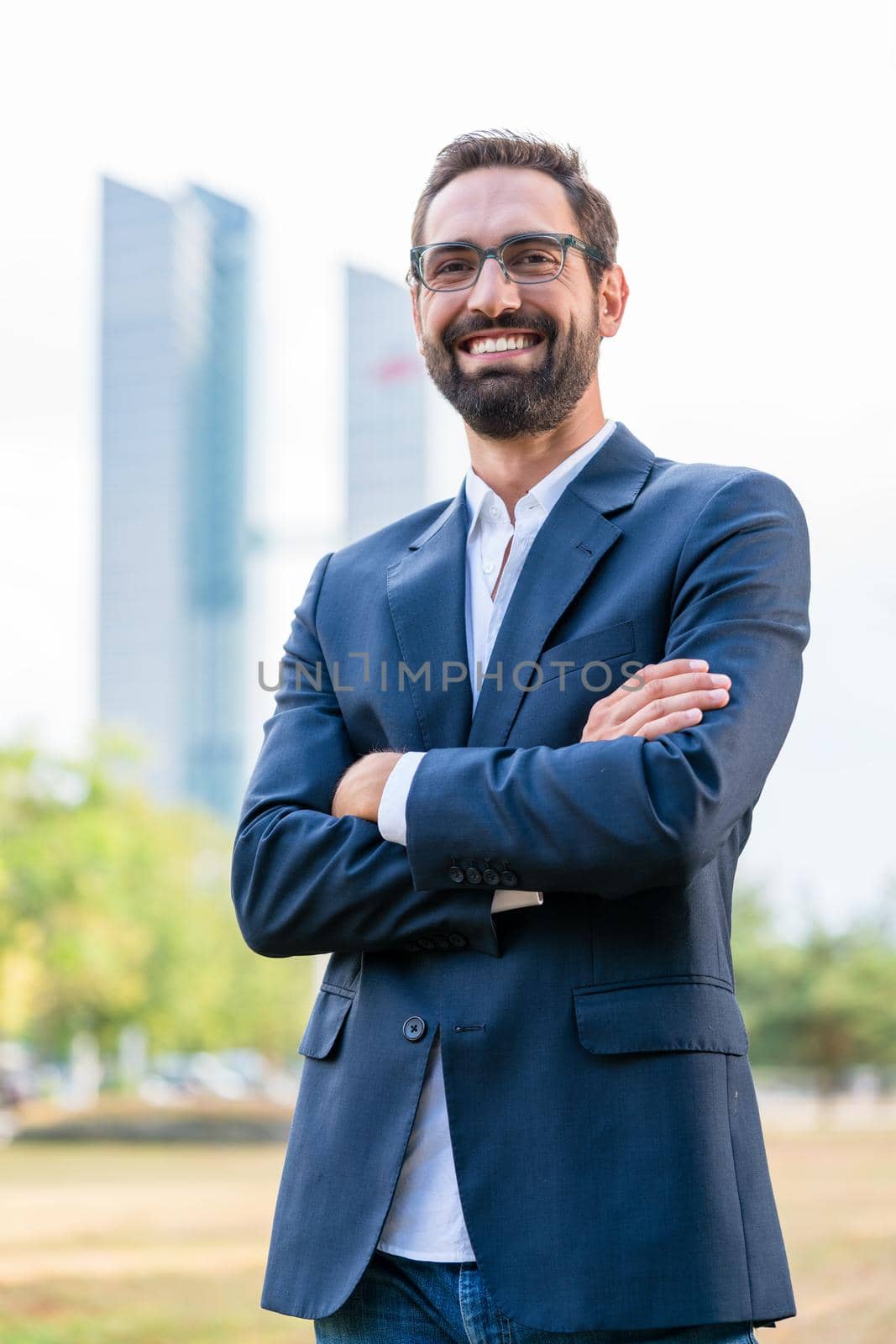 Portrait of smiling businessman with arms crossed standing in the park