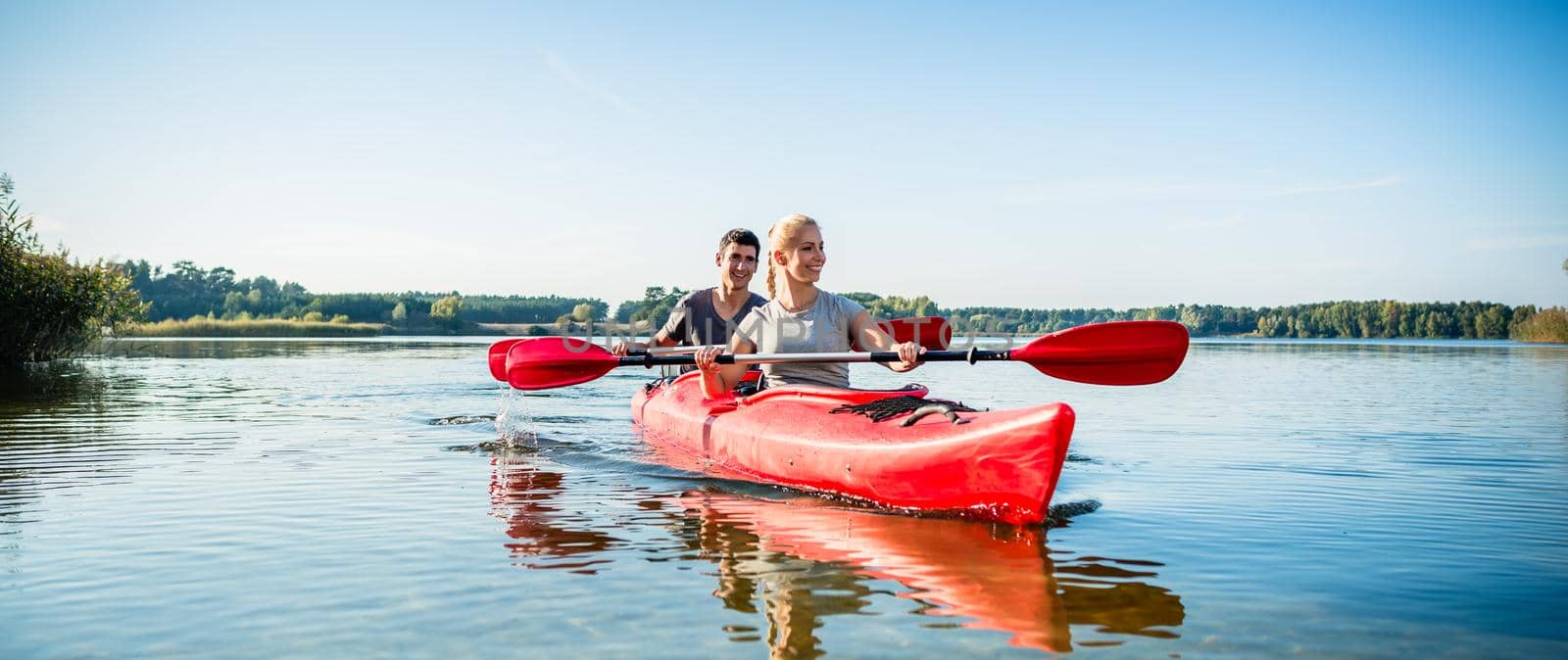 Happy couple kayaking on lake by Kzenon