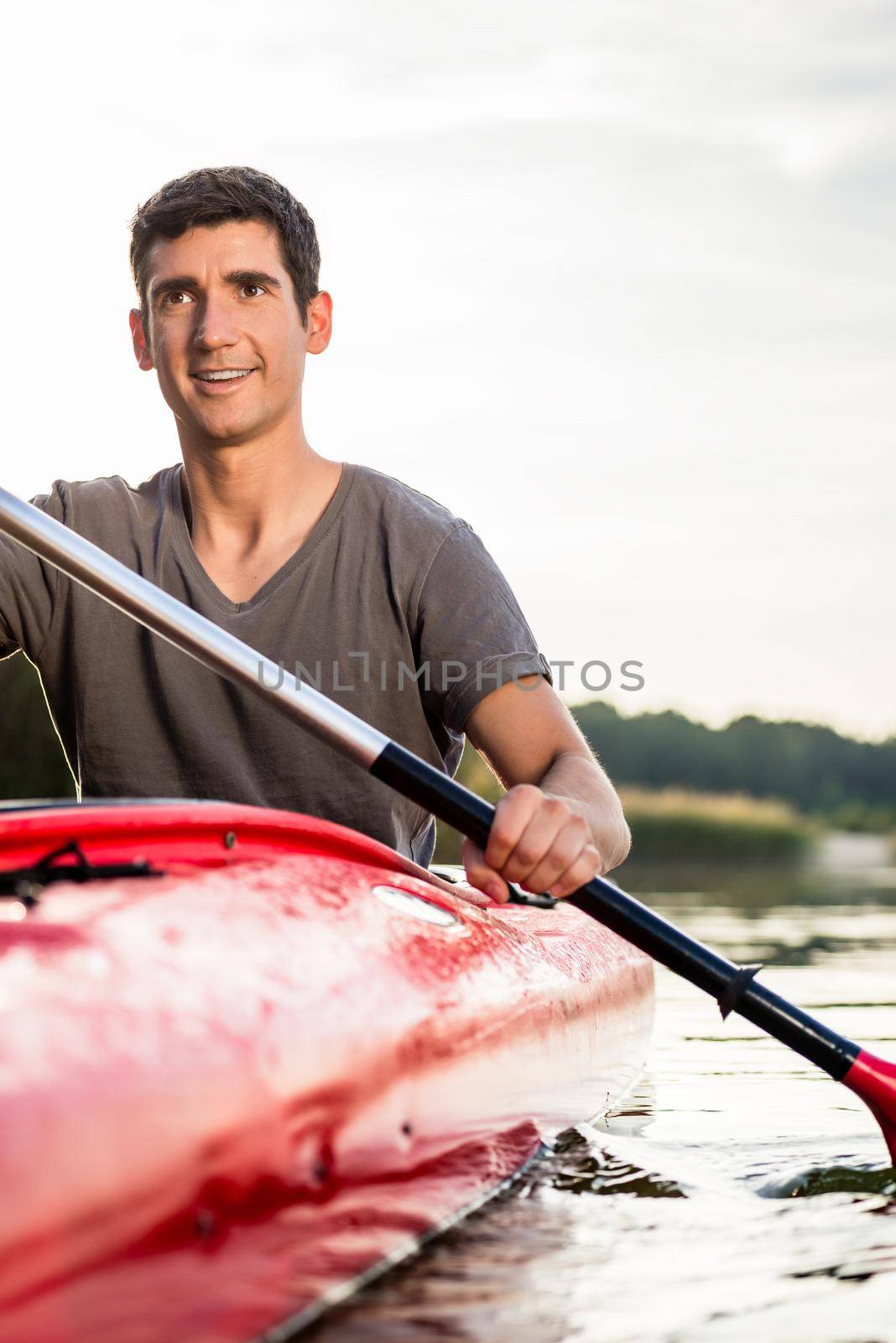 Smiling man rowing in kayak by Kzenon