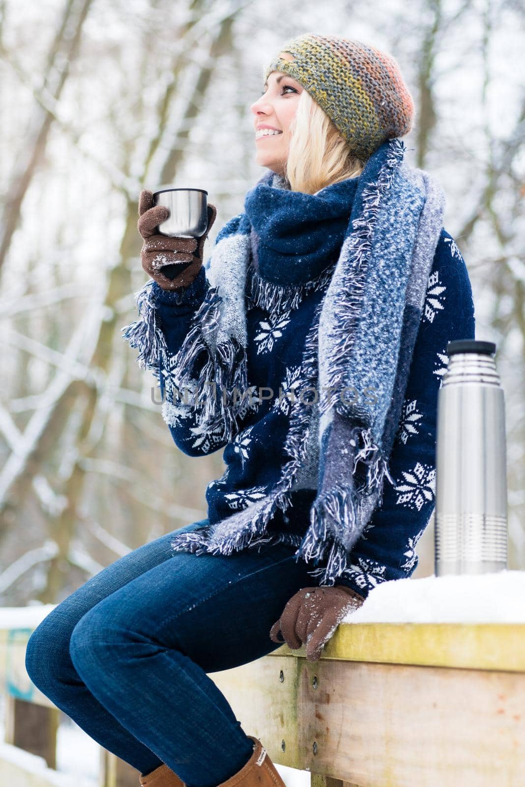 Woman freezing on a cold winter day warming herself up with hot drink in the snow