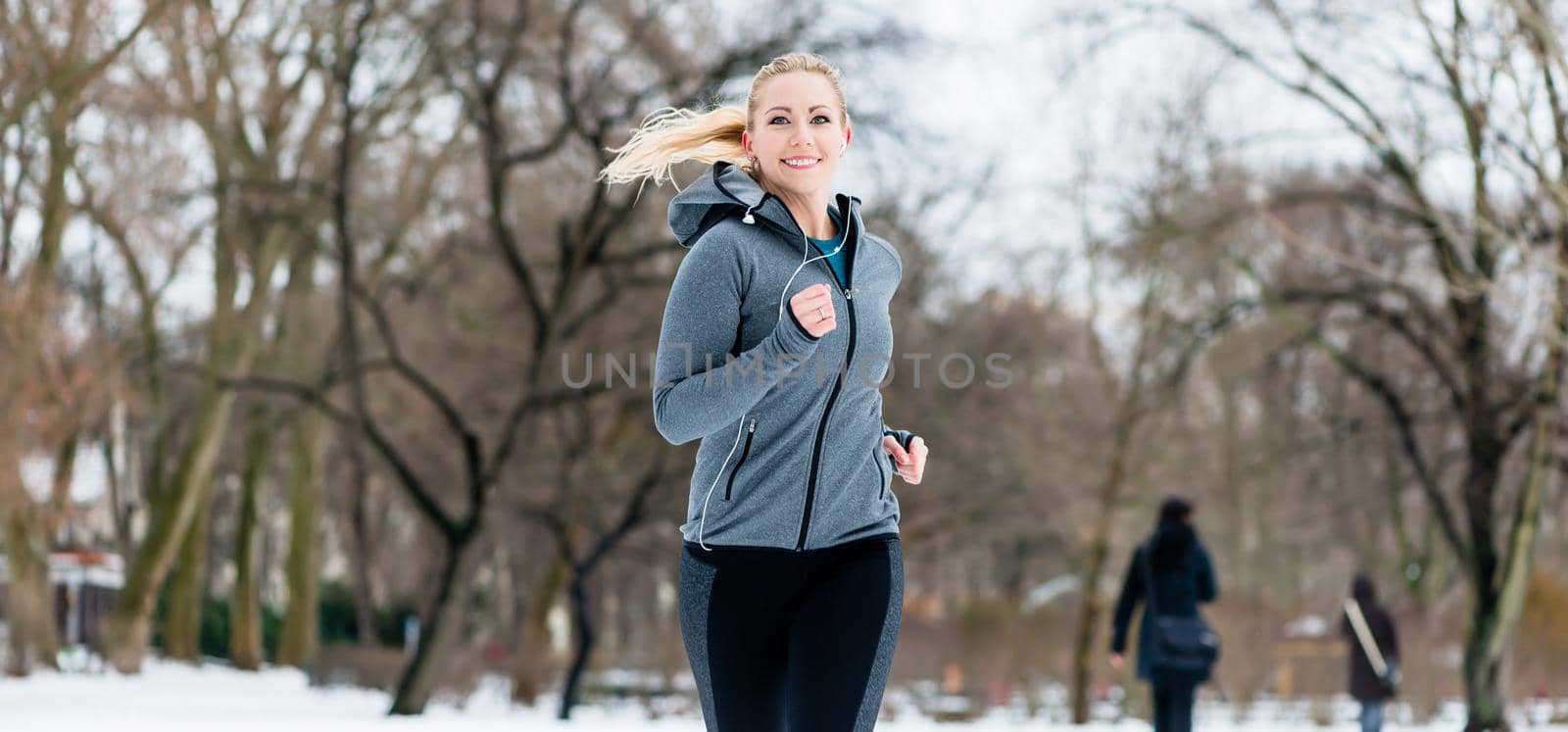 Woman running or jogging down a path on winter day in park