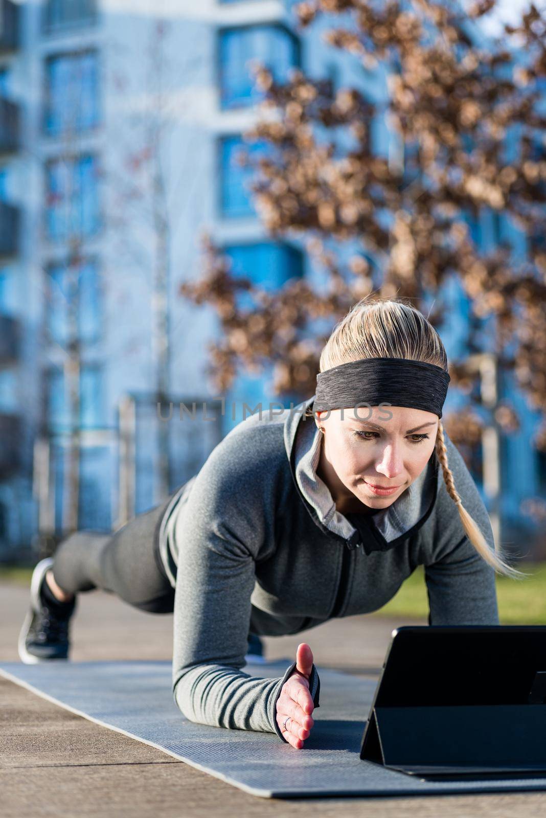 Young woman watching a motivational video while exercising outdoors by Kzenon
