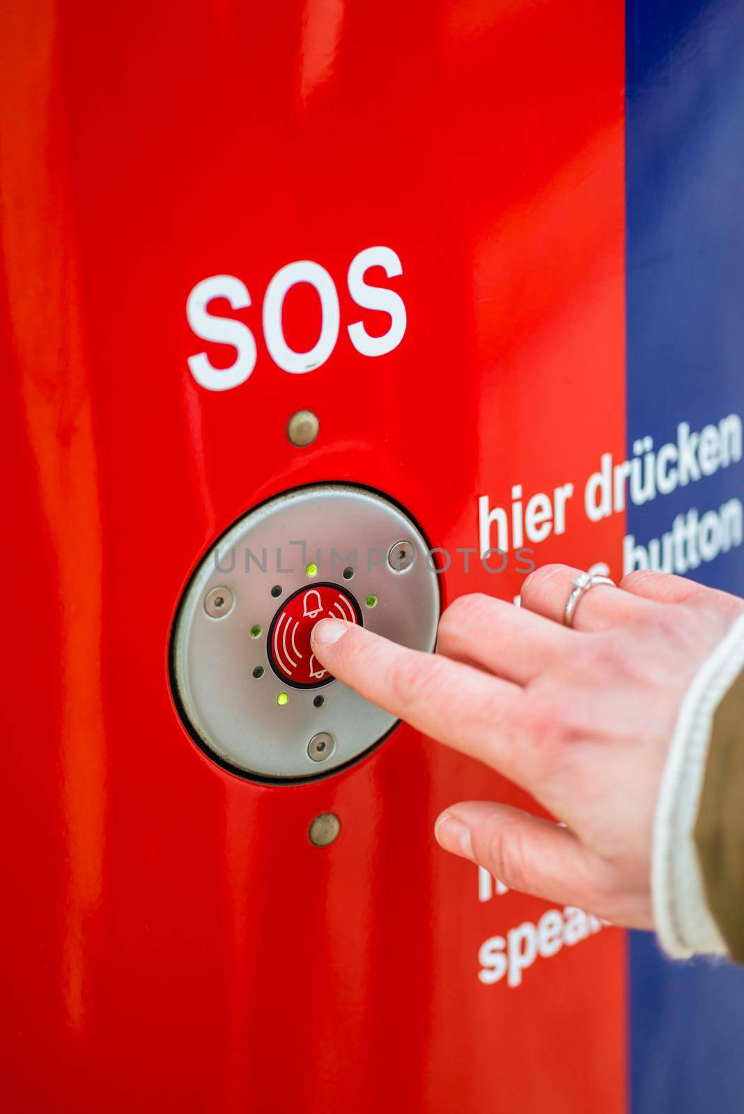 Woman pressing SOS emergency button in train station, only finder to be seen