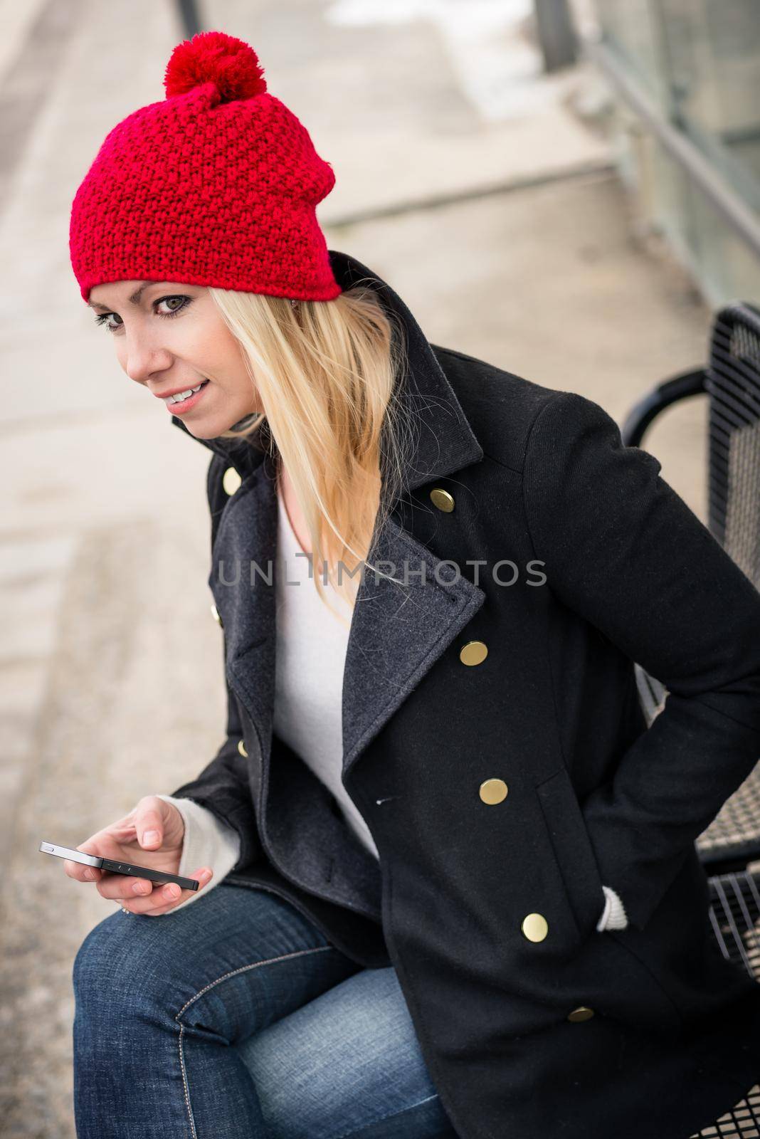 Woman using phone while waiting for a suburban train by Kzenon