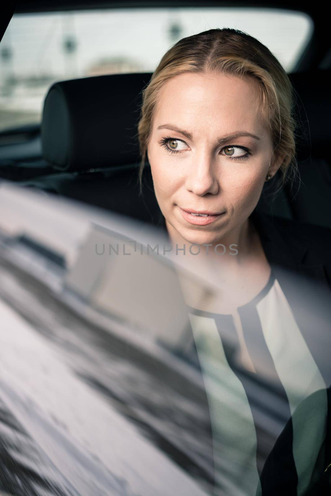 Confident young businesswoman travelling by car seen through car window