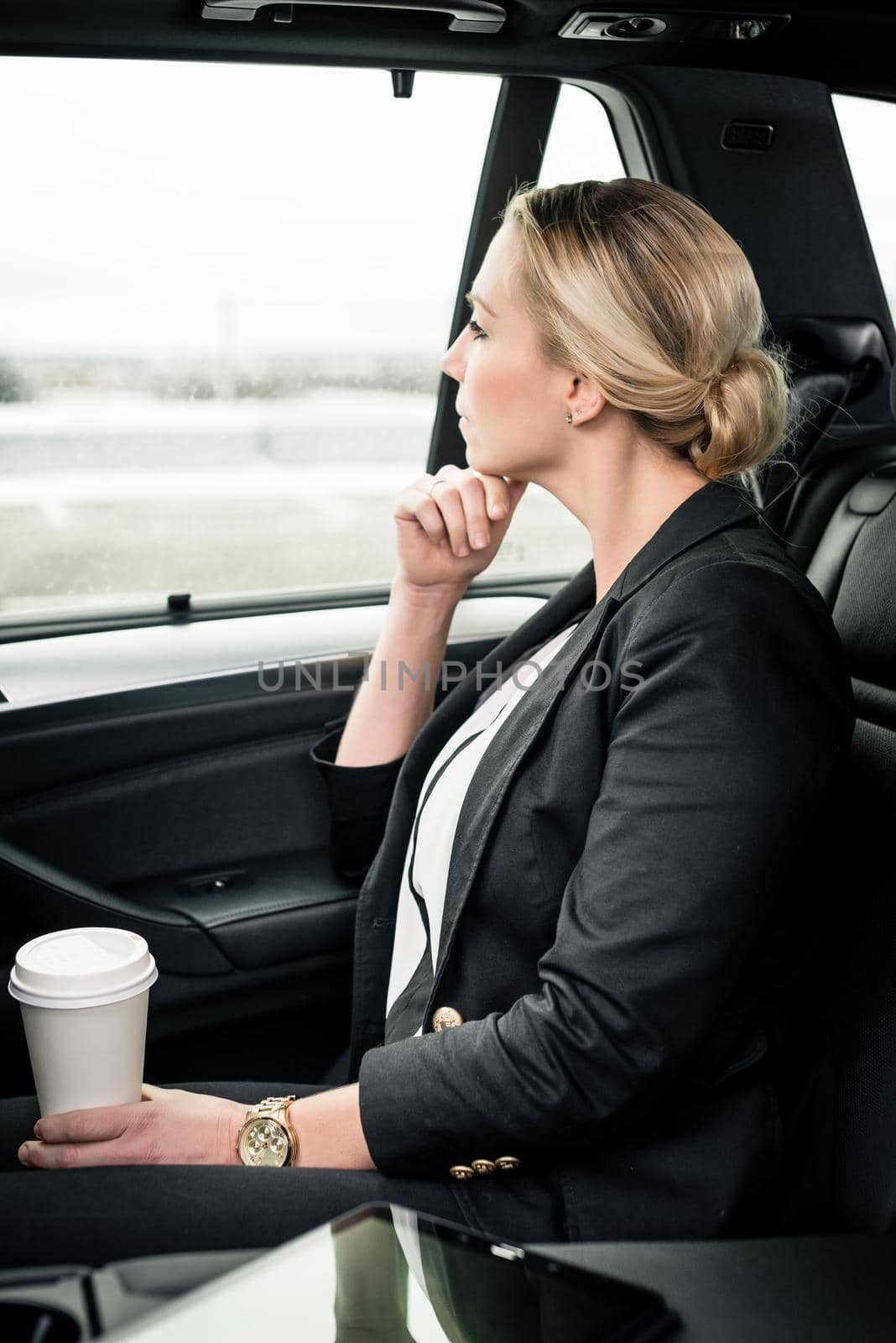 Contemplated businesswoman holding coffee cup sitting in the car by Kzenon