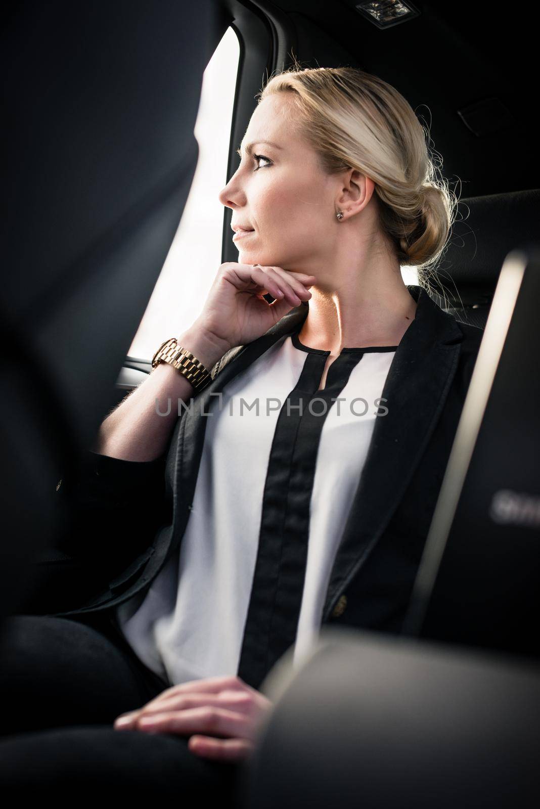 Stylish young businesswoman sitting in car by Kzenon
