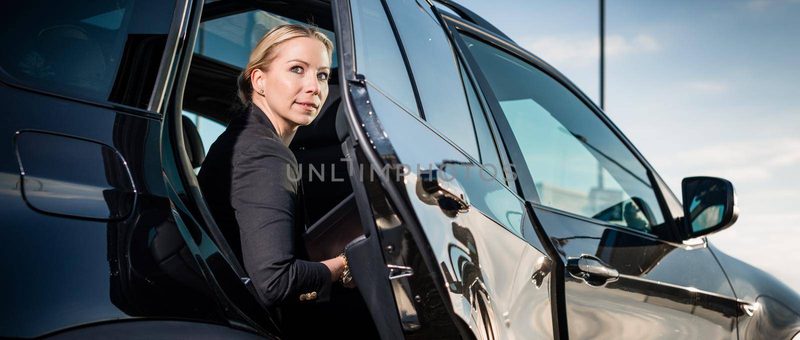 Portrait of businesswoman sitting inside car with door open